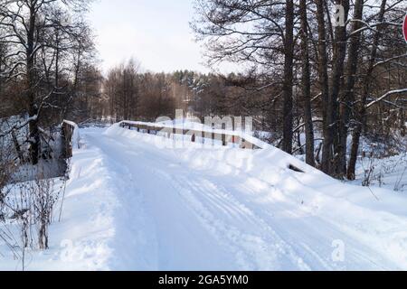 Winter road over a wooden bridge in the forest. Beautiful landscape in the countryside Stock Photo