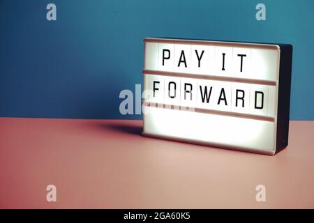 Pay it Forward text message in lightbox on blue and pink background Stock Photo