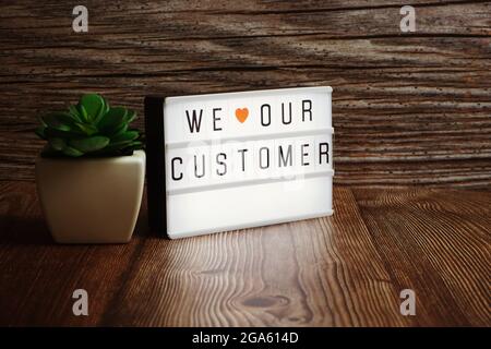 We Love Customer text message in light box on wooden background Stock Photo