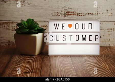 We love our customer text message in light box on wooden background Stock Photo