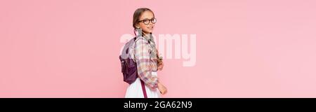 Preteen schoolgirl with backpack looking at camera isolated on pink, banner Stock Photo
