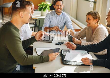 Executives in a meeting discussing on creative ideas.  Co-workers sitting at table having project meeting. Stock Photo