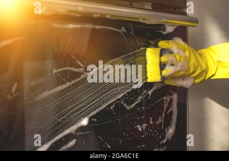 Home kitchen cleaning and housework background, woman washes ove door close-up Stock Photo