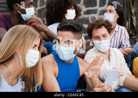 Young diverse people having fun together wearing safety masks outdoor in the city - Focus on drag queen face Stock Photo