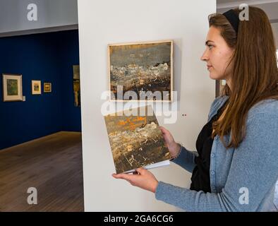 The Scottish Gallery, Edinburgh, Scotland, United Kingdom, 29th July 2021. Edinburgh Art Festival: Pictured:  Amy, an intern at The Scottish Gallery, with one of Joan Eardley’s paintings called Winter Sea which features on the cover of the exhibition catalogue. A new exhibition of the well-known Scottish artist Joan Eardley opens as part of the Edinburgh Art festival during August in a tribute to the centenary of her birth in 1921 Stock Photo