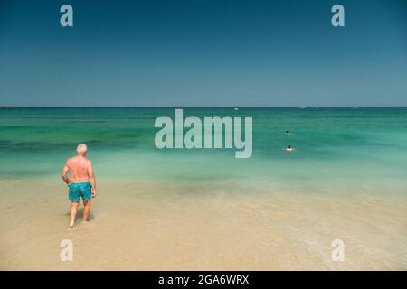 An elderly man ebtering the sea on Porthmeor Beach at St Ives in Cornwall, UK. Stock Photo