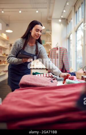 Female Small Business Owner Checks Stock In Shop Using Digital Tablet Stock Photo