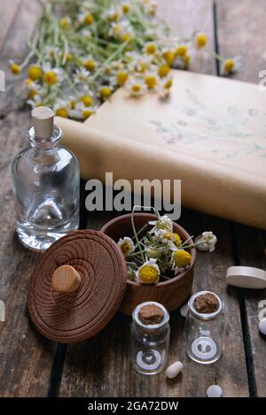 Old book with dry flowers in mortar on table close up