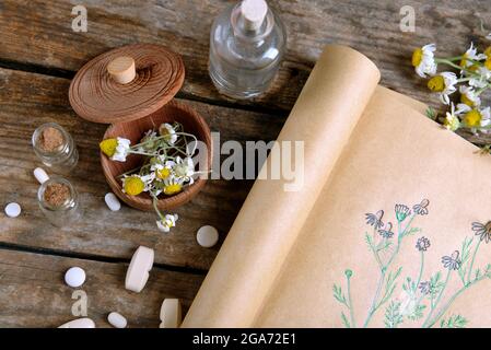 Old book with dry flowers in mortar on table close up