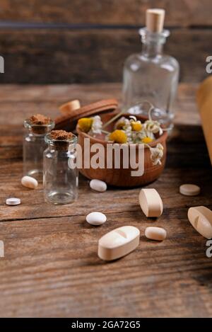 Dry flowers in mortar with tablets on table close up