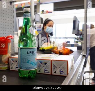 Young woman worker wearing covid facemask in Co Op supermarket working on till at food checkout counter in pandemic Great Britain UK   KATHY DEWITT Stock Photo