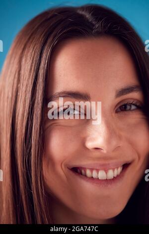 Close Up Studio Portrait Of Confident Young Woman Looking Into Camera Against Blue Background Stock Photo