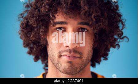 Portrait Of Confident Man With Serious Expression Looking Into Camera Against Blue Background Stock Photo