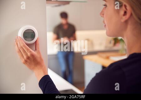 Close Up Of Woman Adjusting Wall Mounted Digital Central Heating Thermostat Control At Home Stock Photo