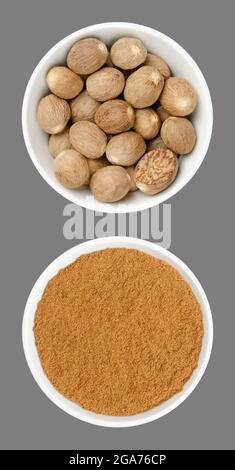 Whole nutmegs and nutmeg powder, in white bowls, on gray background. Fragrant or true nutmeg, dried seeds of Myristica fragrans, a spice. Stock Photo