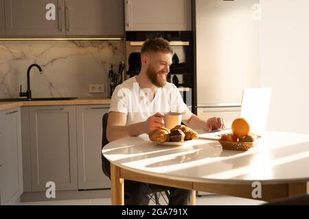 Man using laptop and drinking tea at table Stock Photo