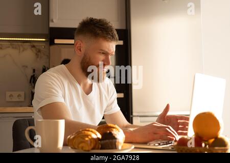 Young tense man using laptop computer at table Stock Photo