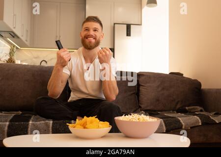 Pleased man sit on sofa and watching TV or movie Stock Photo