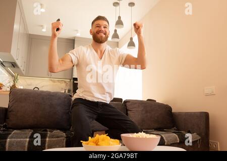 Celebrating man sit on sofa and watch TV or movie Stock Photo