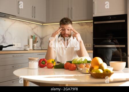 Man sit at table with ingredients for salad Stock Photo