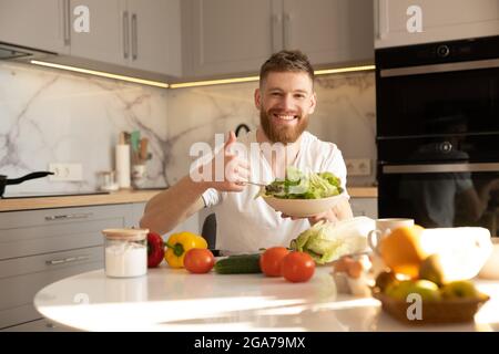 Man showing salad in bowl and thumb up gesture Stock Photo