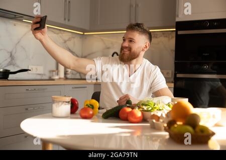 Young man take selfie on mobile phone at table Stock Photo