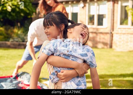 Asian Family In Garden At Home Putting Up Tent For Camping Trip Together Stock Photo