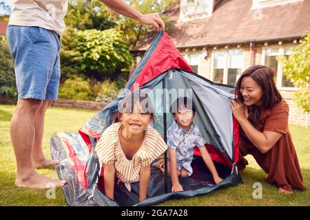 Asian Family In Garden At Home Putting Up Tent For Camping Trip Together Stock Photo