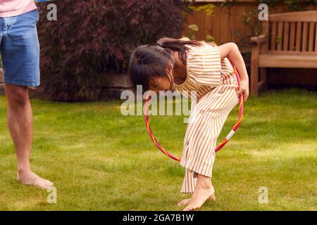 Asian Father And Daughter Having Fun Playing With Hula Hoop In Garden At Home Stock Photo