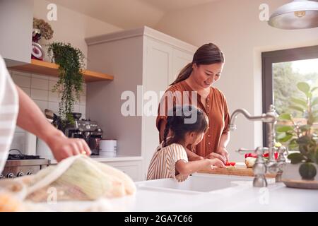 Asian Family Preparing Ingredients For Meal In Kitchen At Home Together Stock Photo
