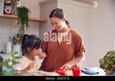 Asian Family Preparing Ingredients For Meal In Kitchen At Home Together Stock Photo