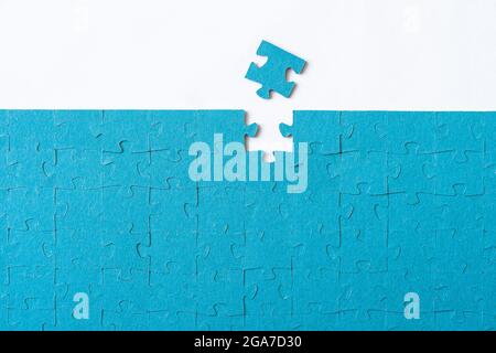 Last piece of puzzle lying separately on white background. the puzzle is assembled Stock Photo