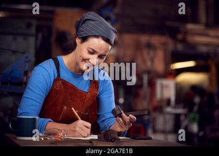 Female Blacksmith Wearing Headscarf Working On Design In Forge Stock Photo