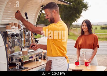 Couple Running Independent Mobile Coffee Shop Preparing Drink Standing Outdoors Next To Van Stock Photo