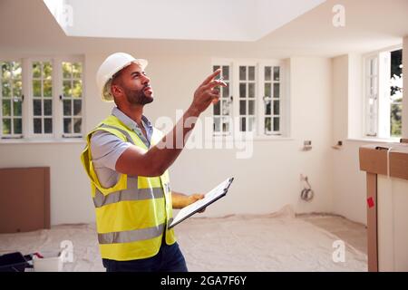 Building Surveyor Wearing Hard Hat With Clipboard Looking At Interior Of New Property Stock Photo