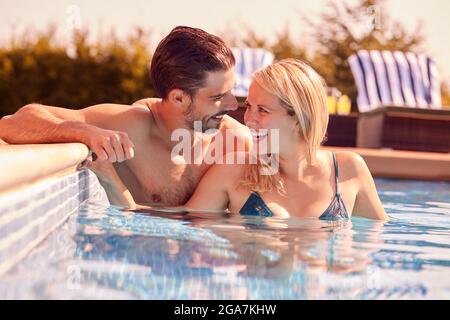 Couple Having Fun On Summer Vacation Relaxing In Outdoor Swimming Pool Stock Photo