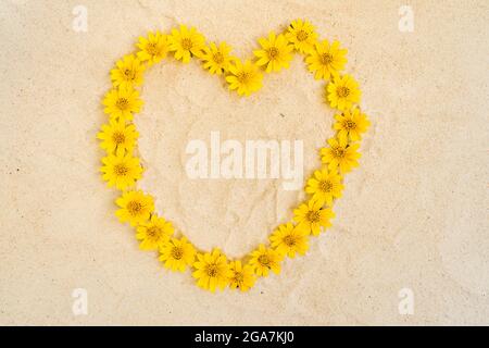 Overhead shot of a heart shape figure on paper made of yellow flower heads Stock Photo