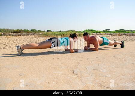 Smiling caucasian couple doing plank, core workout. Stock Photo