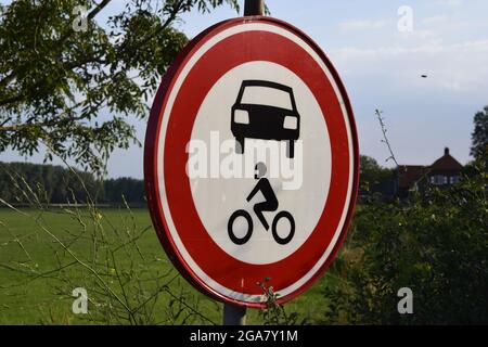 DIEREN, NETHERLANDS - Apr 14, 2021: A shot of a sign in front of a fully green field stating that moter cycles and cars are not allowed. Stock Photo