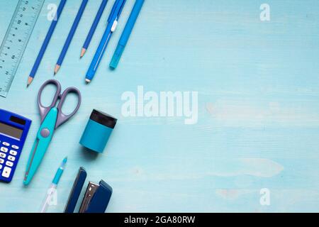 blue and grey school supplies knolling on blue wood background with copy space, scissors, pencil sharpener, ruler, pencils, stapler, eraser and pen Stock Photo