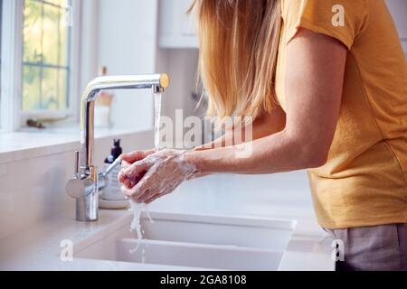 Close Up Of Mature Woman Washing Hands In Kitchen Sink