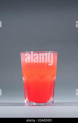 red berry lemonade or strawberry drink with ice in glass on grey background Stock Photo