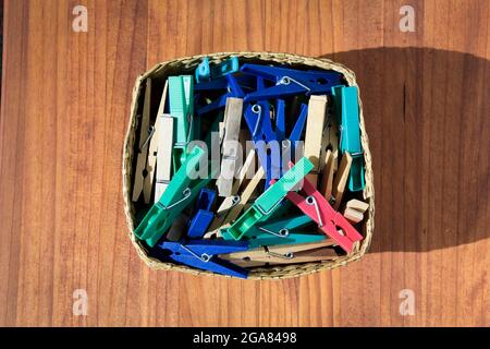 Box full of clothespins on a wooden surface. Stock Photo