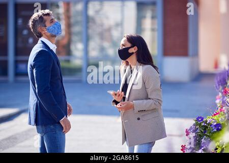 Businessman And Businesswoman Having Socially Distanced Meeting Outdoors In Street Stock Photo