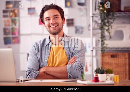 Portrait Of Smiling Male Student Or Business Owner Working In Fashion Using Laptop In Studio Stock Photo