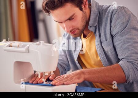 Close Up Of Male Student Or Business Owner Working In Fashion Using Sewing Machine In Studio Stock Photo