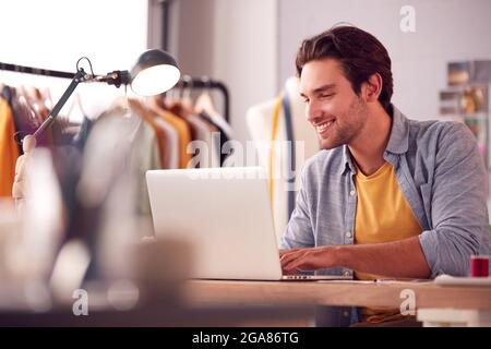 Male Student Or Business Owner Working In Fashion Using Laptop In Studio Stock Photo