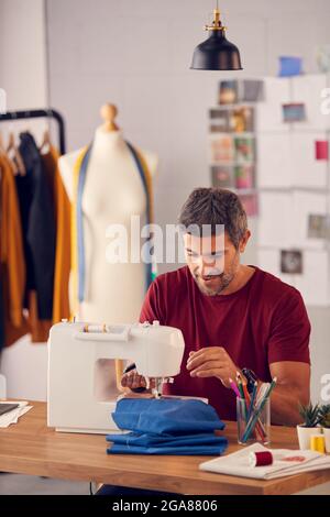 Male Fashion Designer Working On Sewing Machine In Studio Stock Photo