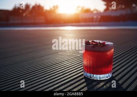 clover club cocktail drink with raspberry and rose petal outdoor at sunset Stock Photo