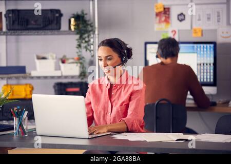 Business Team Wearing Telephone Headsets Talking To Callers In Customer Services Department Stock Photo